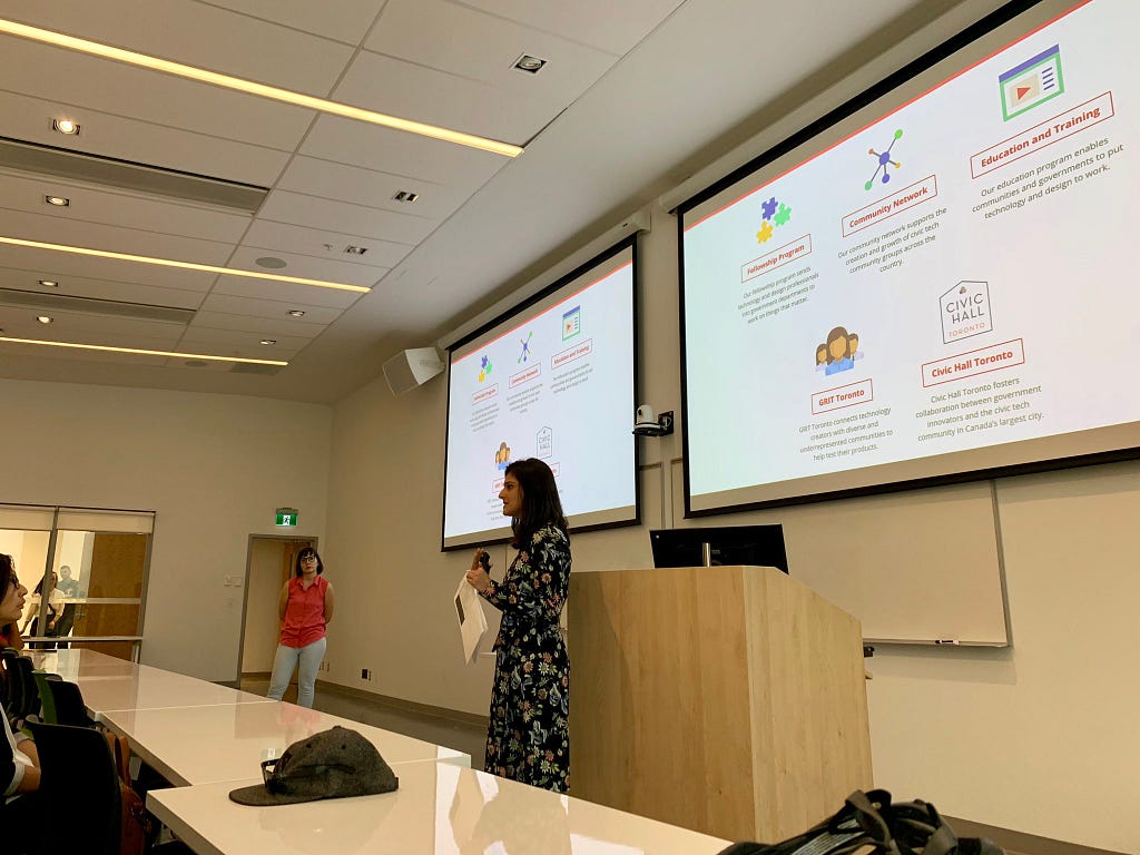 Sabrina Dominguez and Meha Shah  in front of a slide deck showing Code for Canada’s various programs.