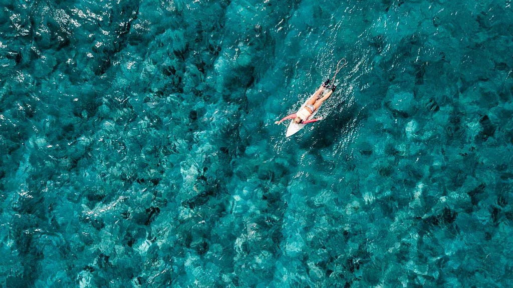 Woman paddling on a surf board in crystal blue water