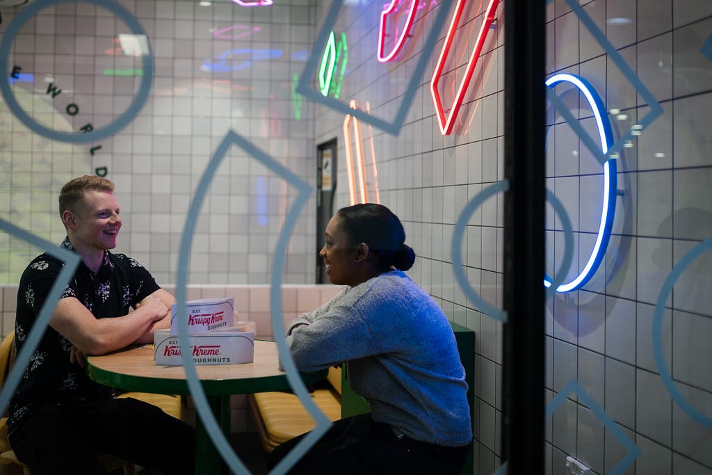 One male and one female seated and both smiling while having a conversation