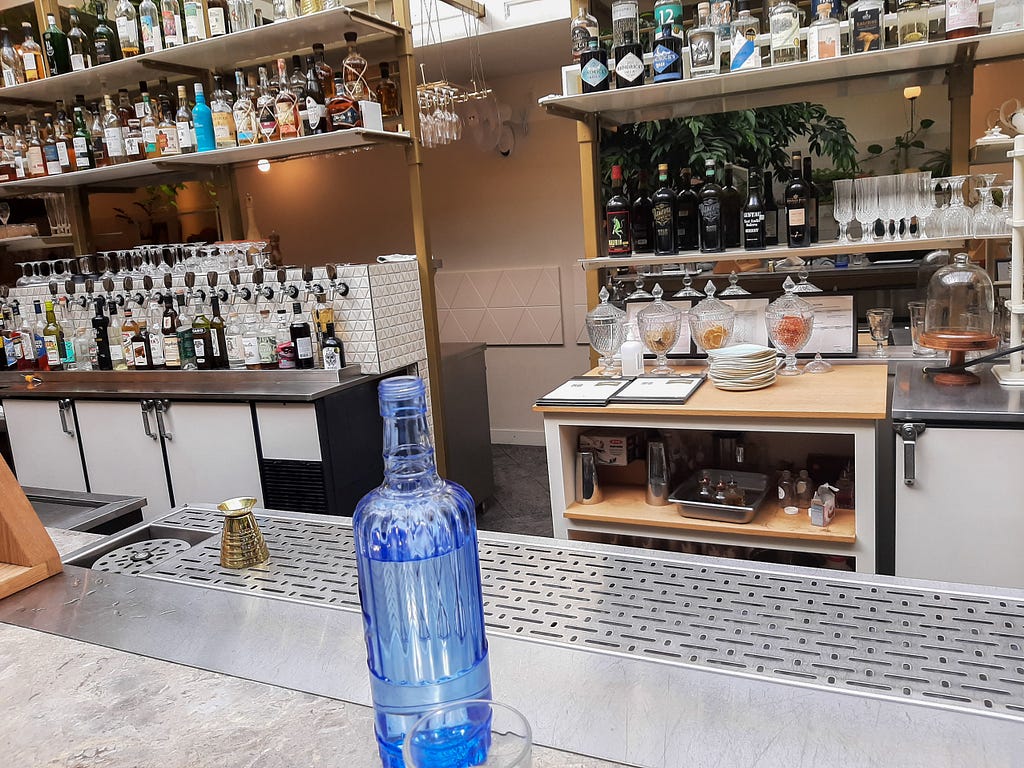 A blue glass bottle sitting on a bar at a restaurant.