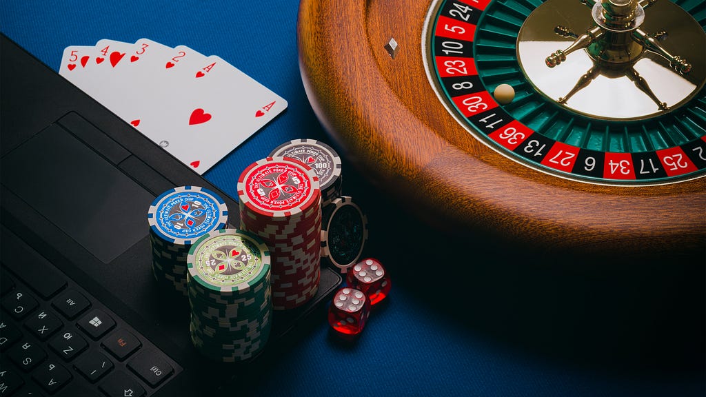 A table with poker chips, a roulette wheel, cards, dice, and a computer