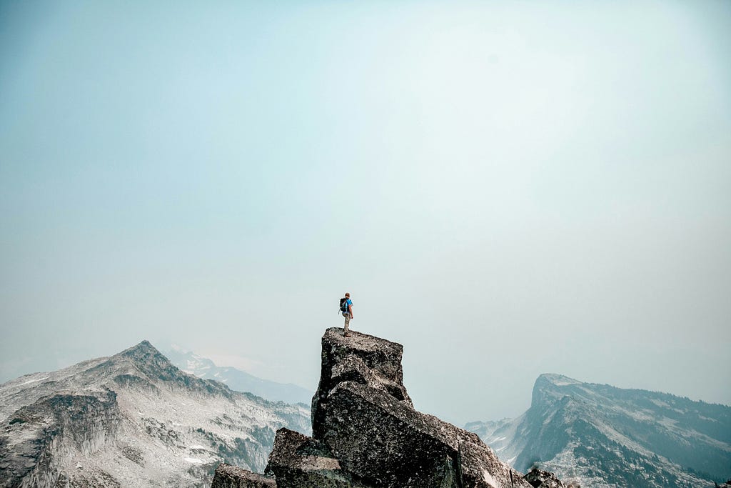 Someone at the top of a mountain under a clear blue sky