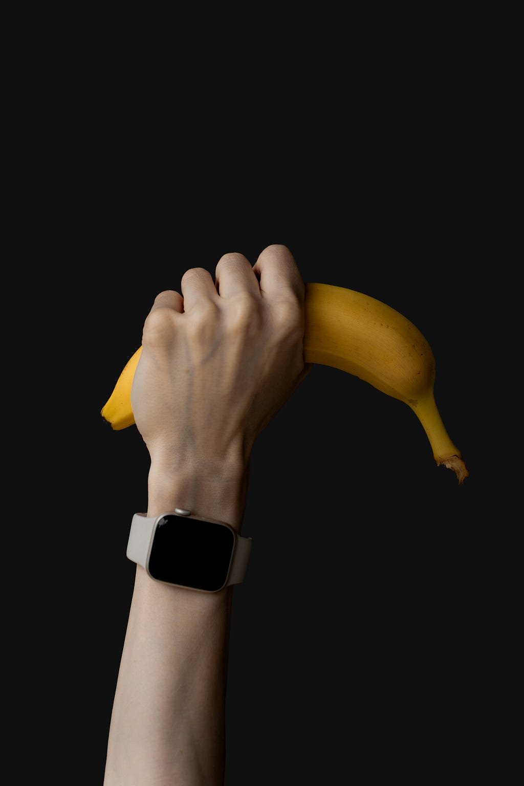 An picture of a banana holding by a hand in the air.