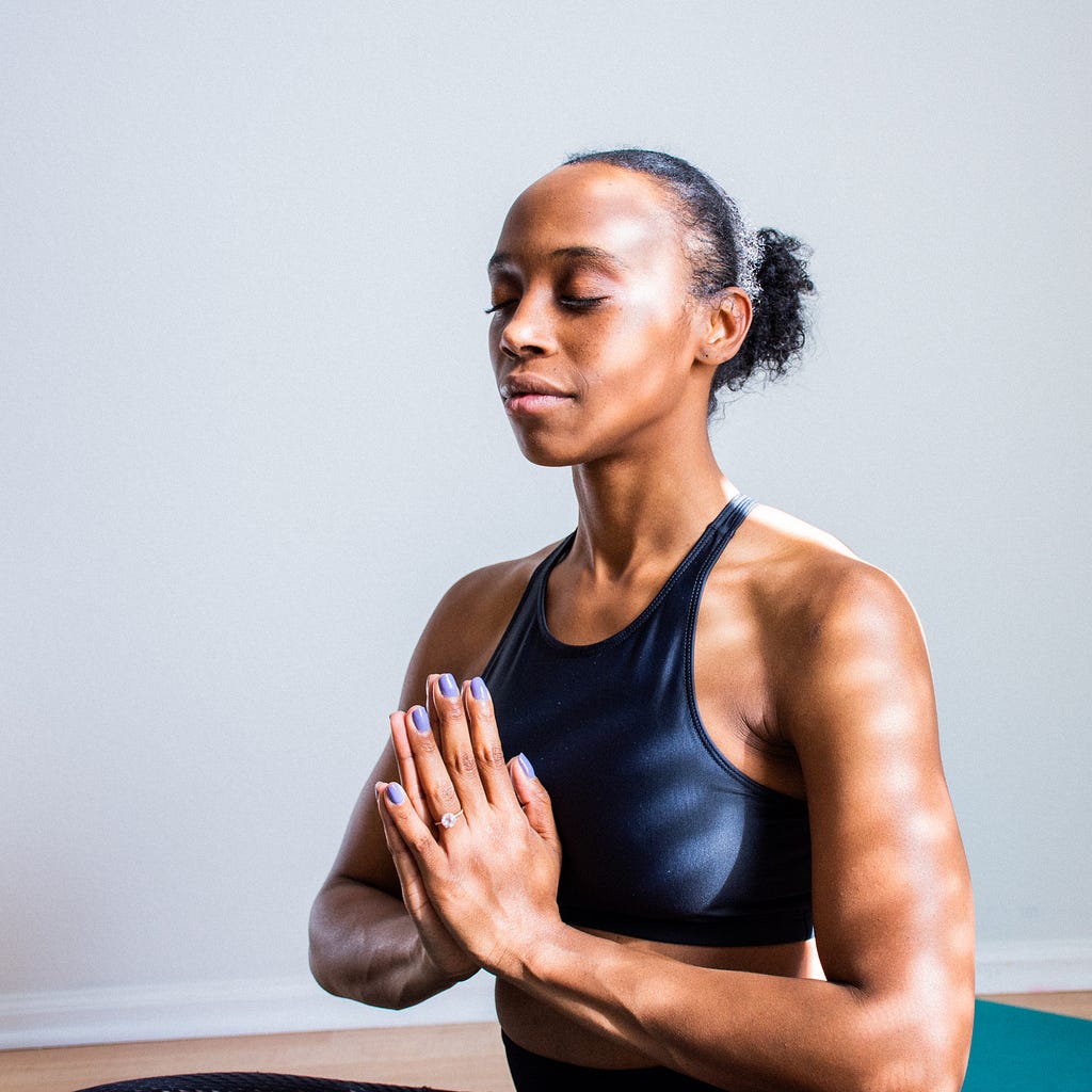 A black woman practicing yoga in a straight posture and with coordinated breathing