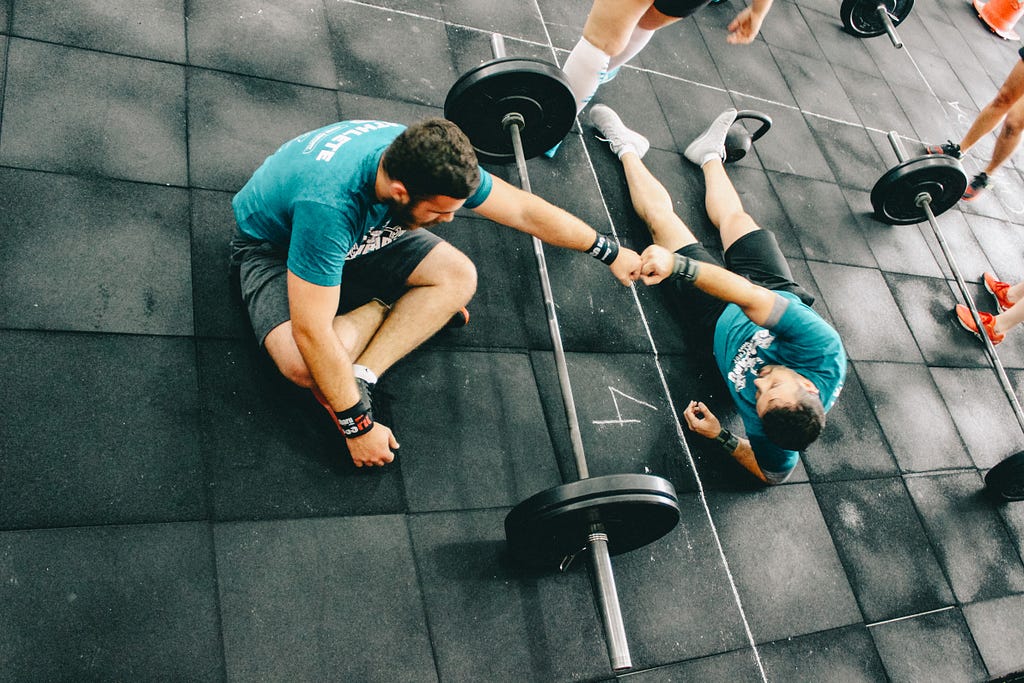 A couple of friends fist-bumping at the gym over some heavy-weight.