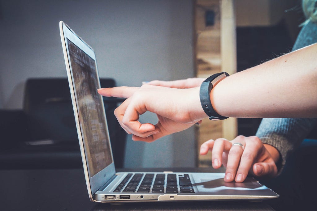 A person points at a laptop screen.