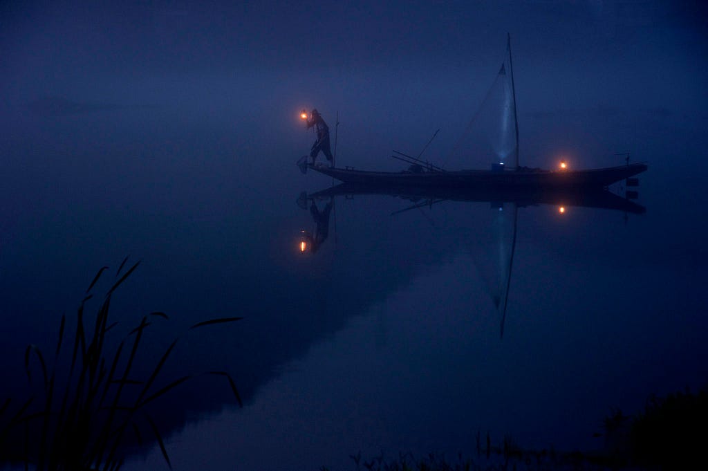 a person sailing in the dark holding a light, representing mental blindness