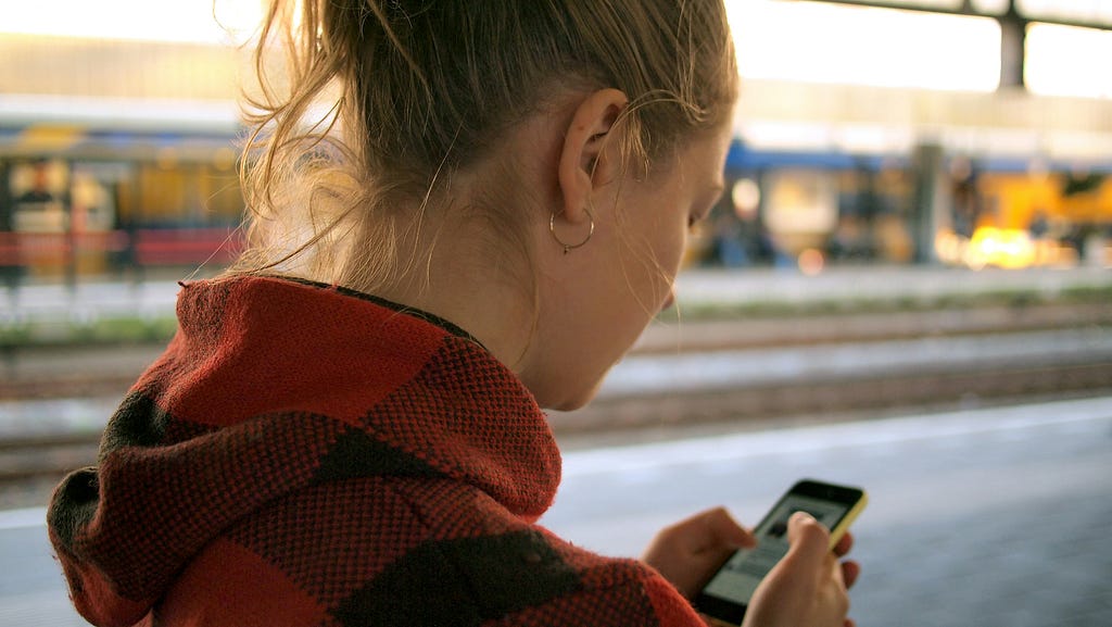 A woman at a train station uses her mobile phone.