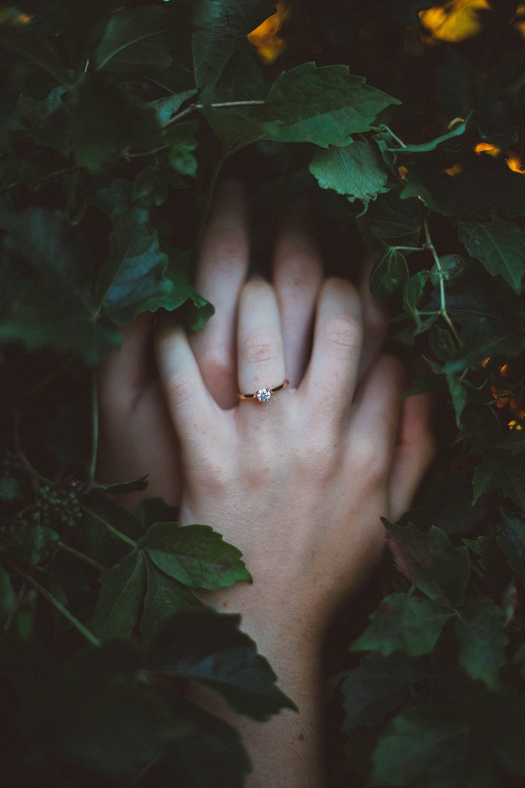 Two hands folded together with a wedding band on the top hand.