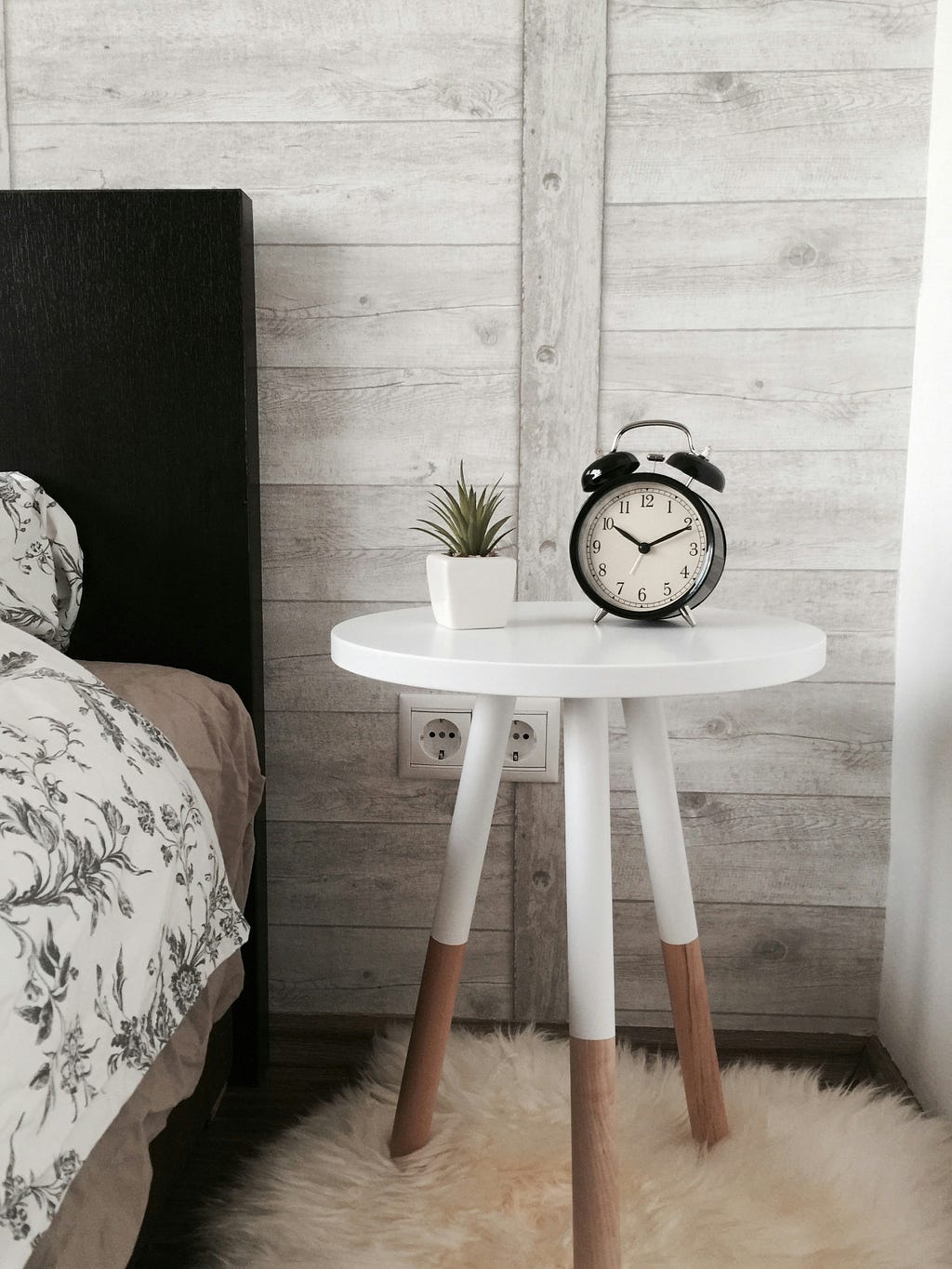 an old fashioned alarm clock on a white bed side table