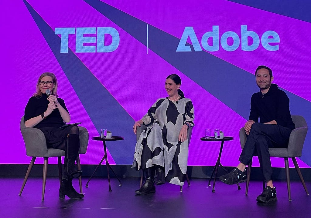 A photograph of Debbie Millman, Honor Harger, and Scott Belsky seated on stage smiling at the audience. The screen behind reads ‘TED | Adobe”.