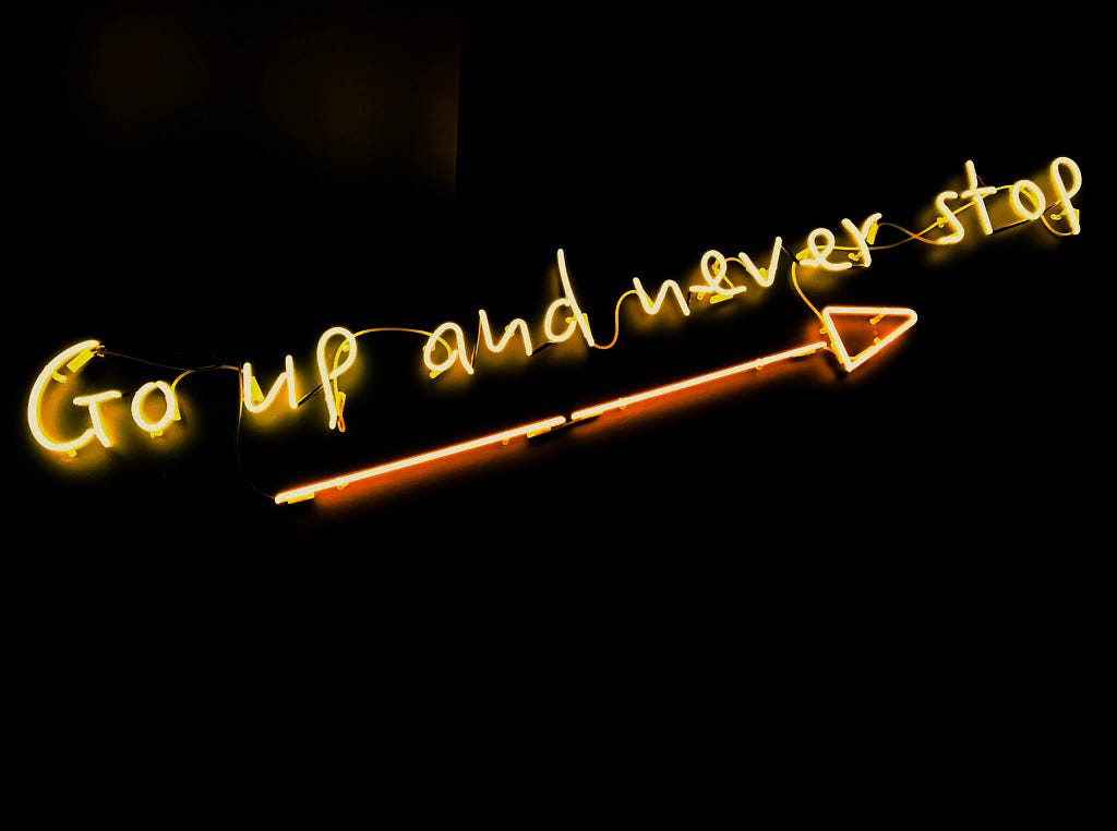 Neon lights saying “Go up and never stop”