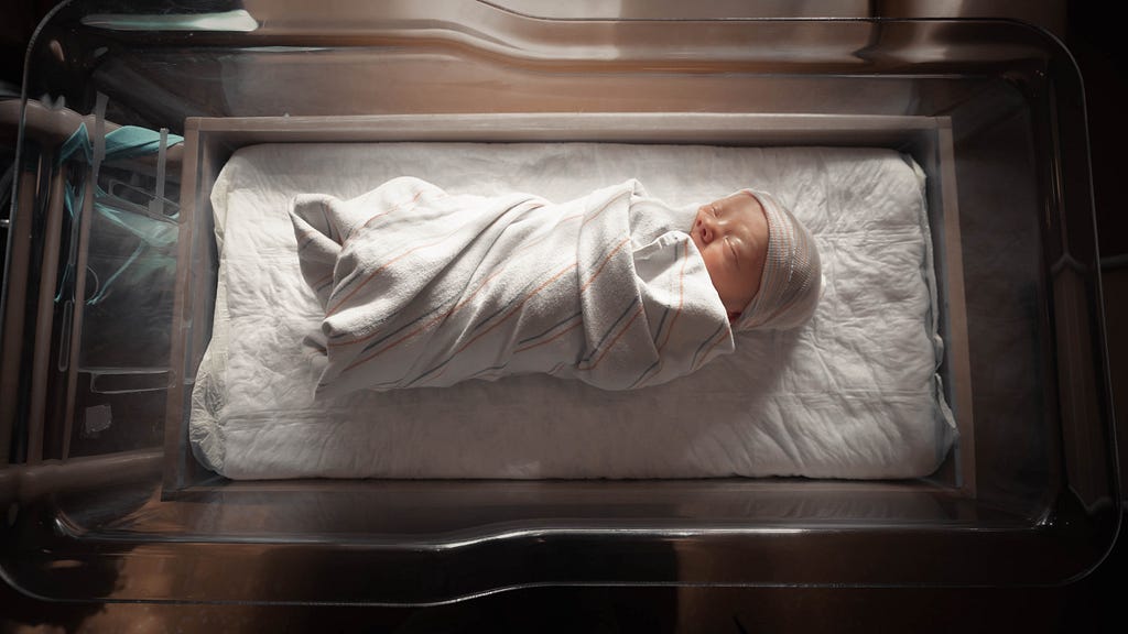 Newborn baby in hospital bassinet.