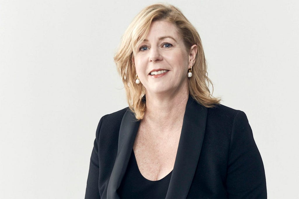 Author Liane Moriarty smiling in a professional headshot, wearing a black blazer against a neutral backdrop