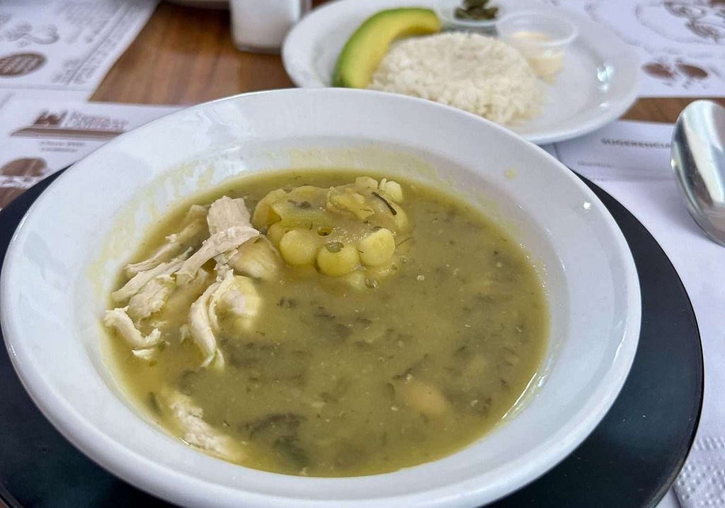 A bowl of ajiaco soup is sitting on a table.