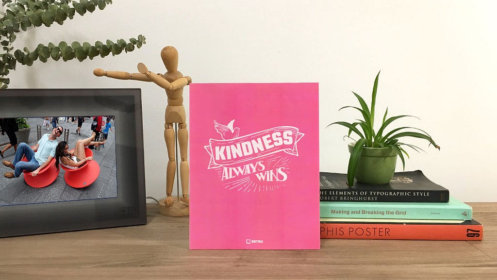 A poster saying ‘Kindness Always Wins’ in an office environment.