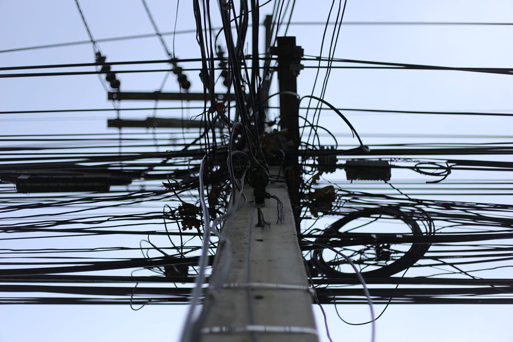 A telephone pole with a massive number of wires attached.