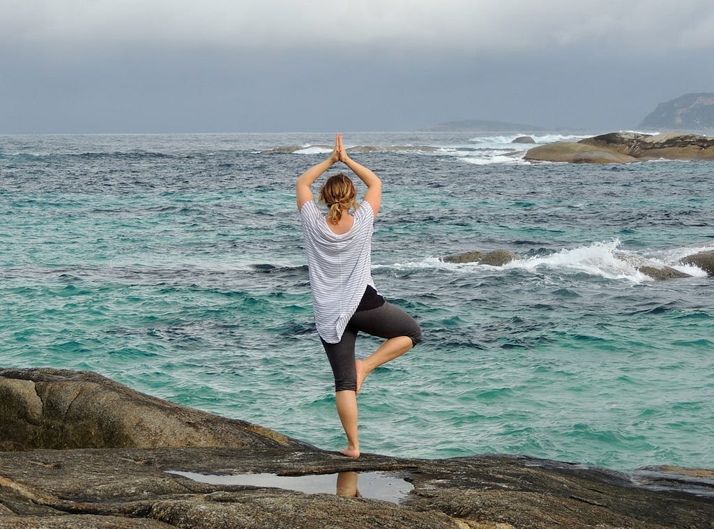 Woman practising yoga on a beach