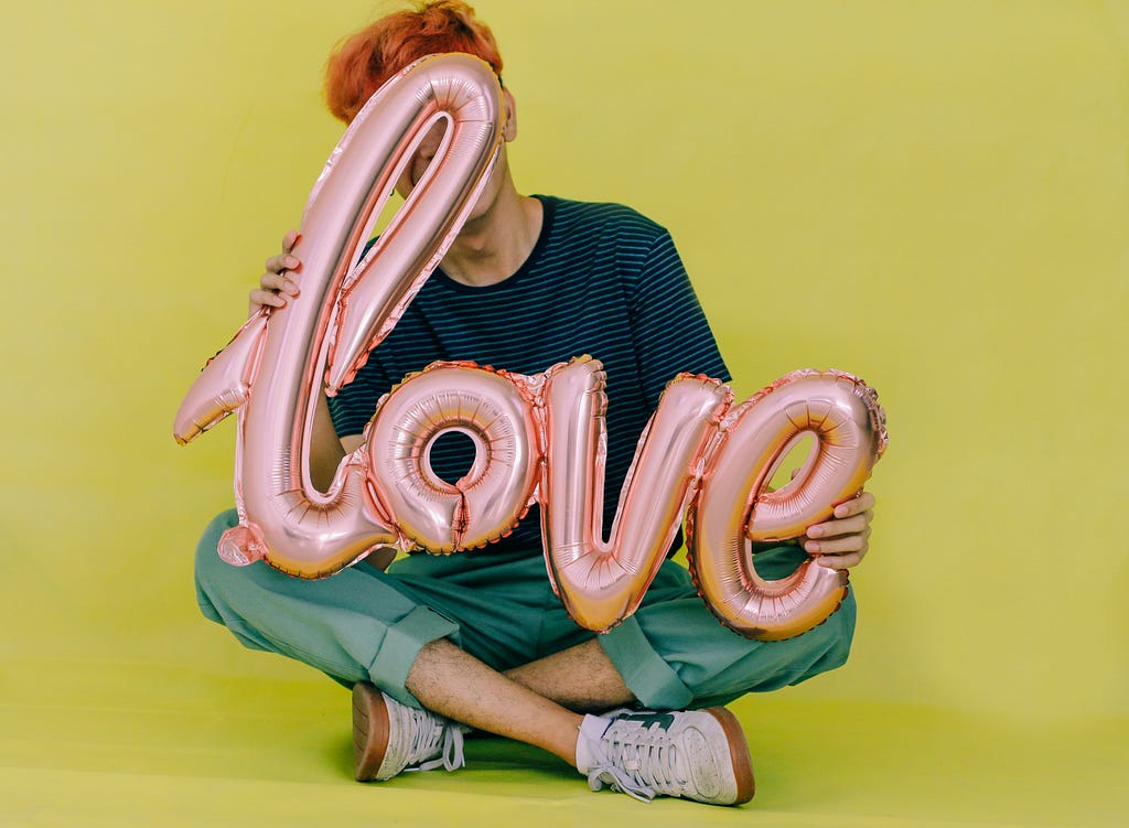 Person holding a balloon with the word “love.”