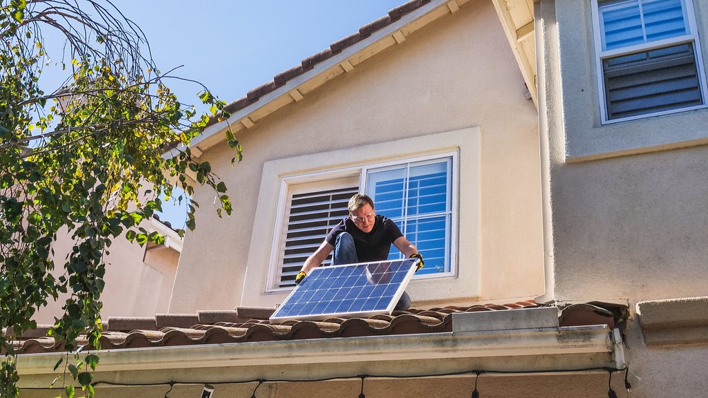Person installing a solar panel on a roof.
