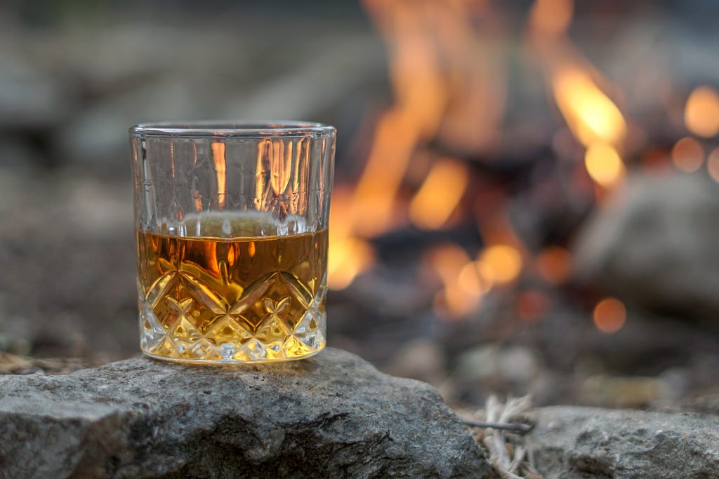 glass of whiskey in front of a fire.
