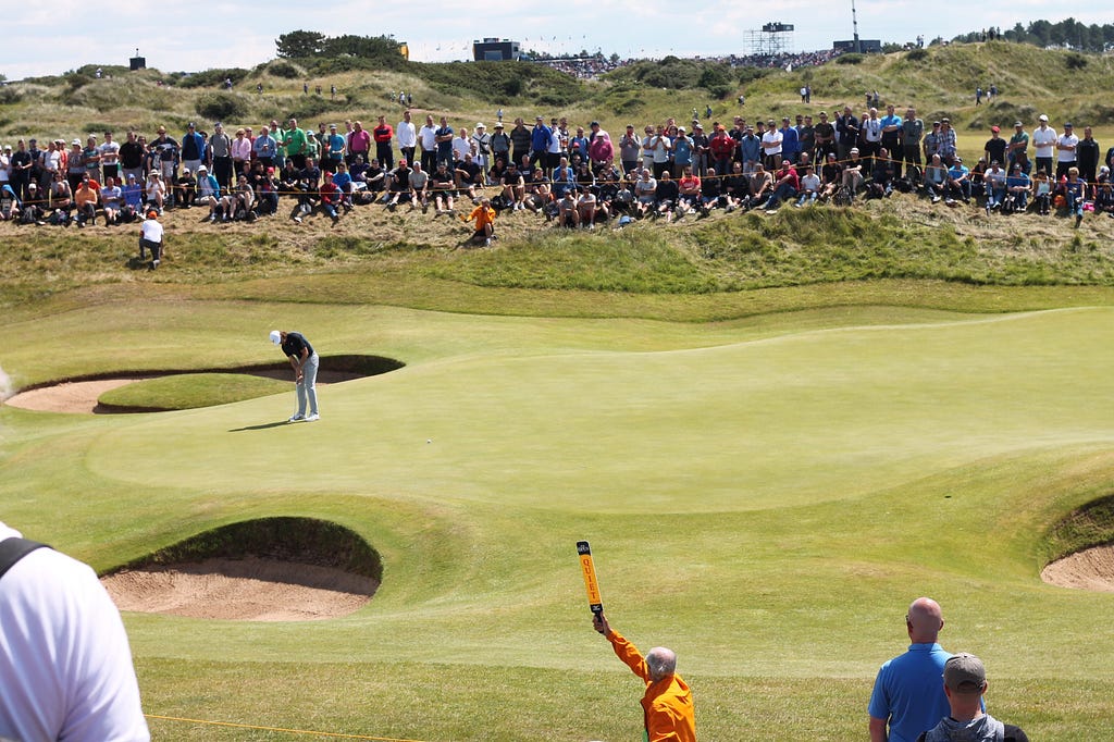 A crowd watches a PGA professional putt uphill.