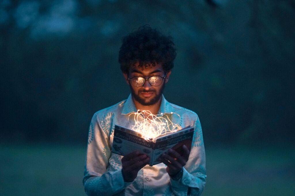 guy holding book and string lights
