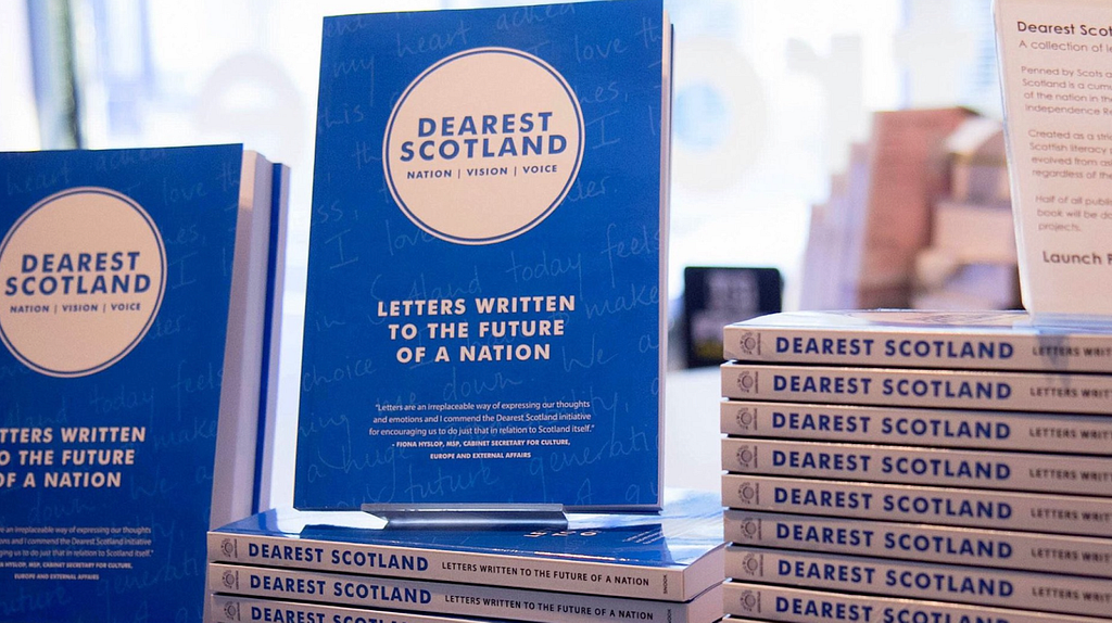 Dearest Scotland books, stark blue colour with a white logo stacked up in Waterstones