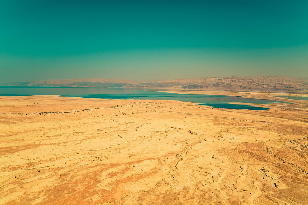 A source of water at the horizon in the middle of a desert landscape