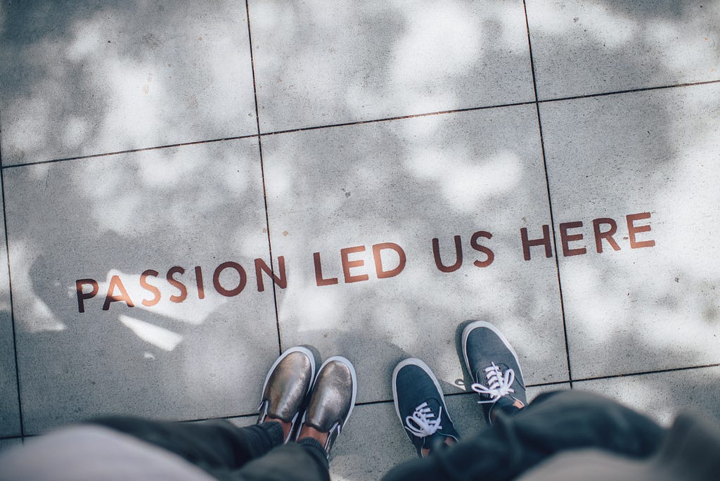 photo of the feet of two people standing outside and letters saying, Passion led us here