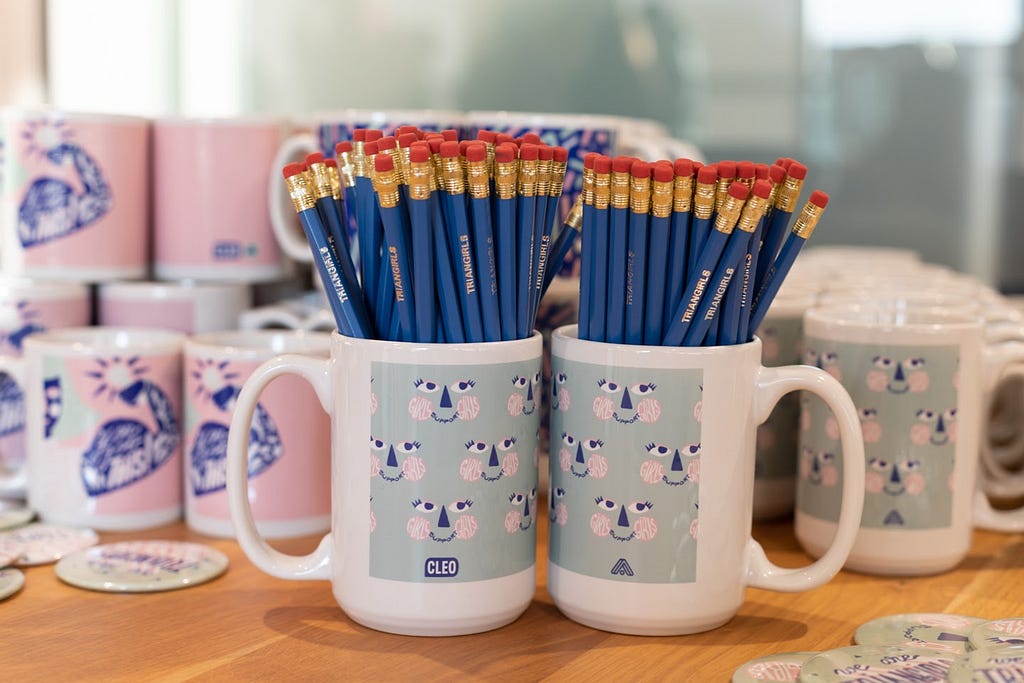 A photo of Triangirls branded mugs filled with branded pencils