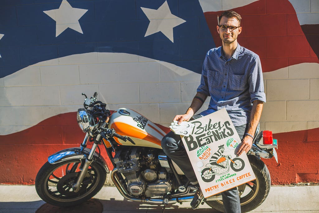 The author posing with poster, cards and motorcycle tank custom designed in senior university design studio.