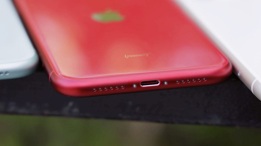 A red iPhone with a lightning connector that won’t be allowed on new devices in the future.