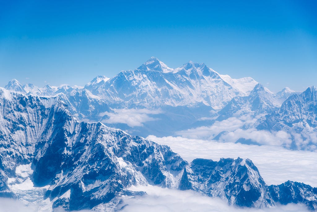 An image shows high mountains covered in snow, giving them a blue and white hue.