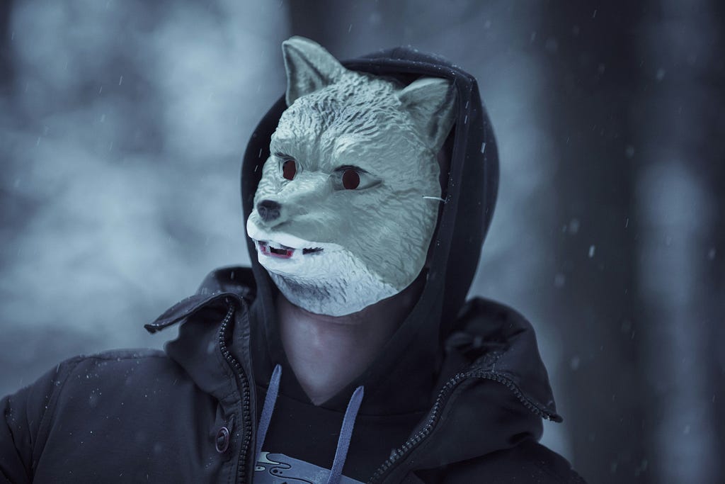 Man with hood and wolf’s mask in a snowy landscape