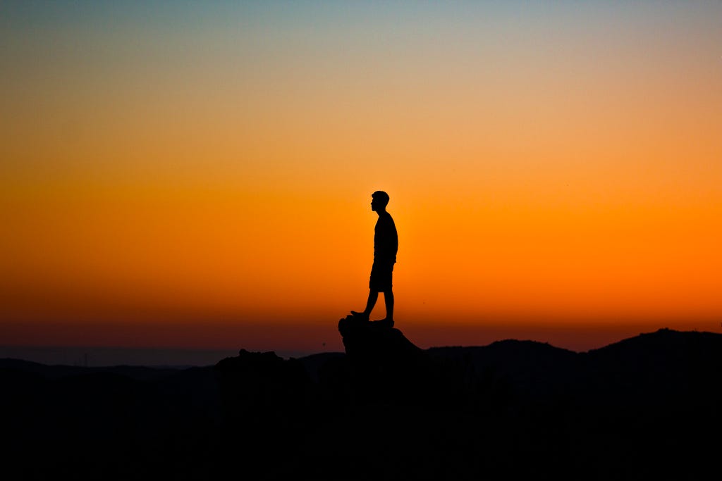 A siluoette of a man standing on a rocky landscape