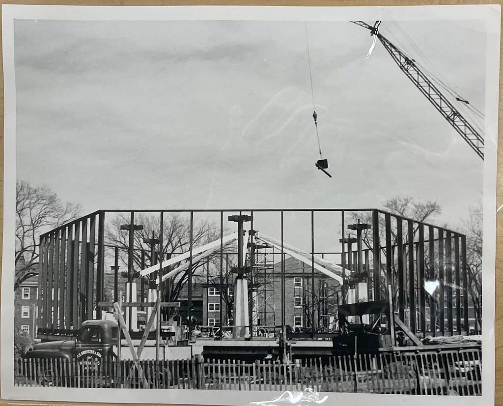 A crane hangs over the octagonal wooden frame of the Weyerhaeuser Chapel.