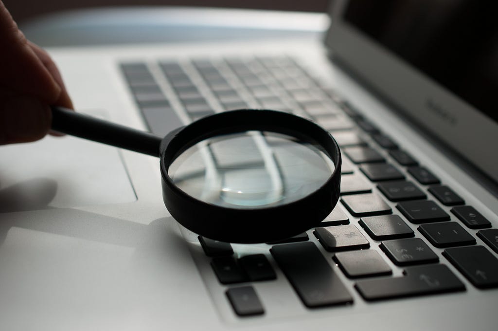 A zoomed in magnifying glass inspecting the keys on a keyboard on a laptop.