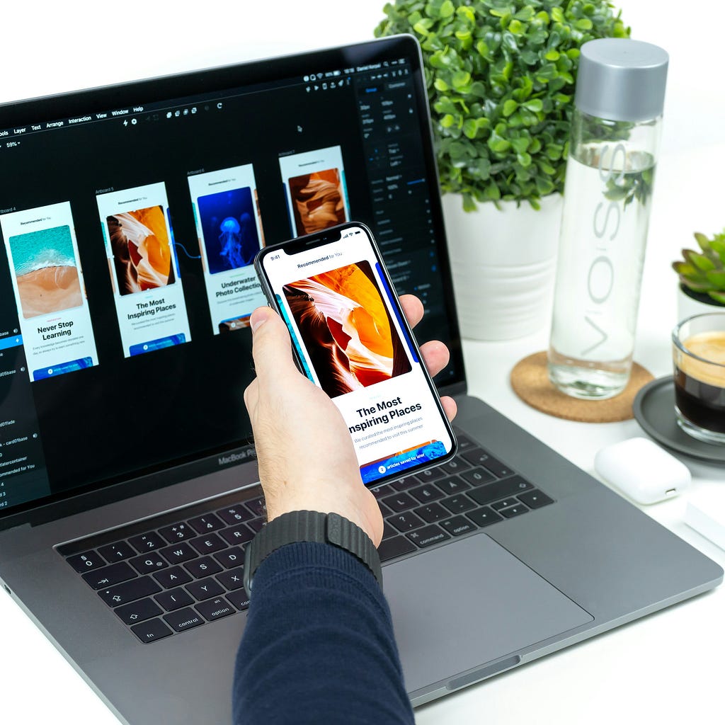 A man holds a smartphone in front of aniterface designs for that app.