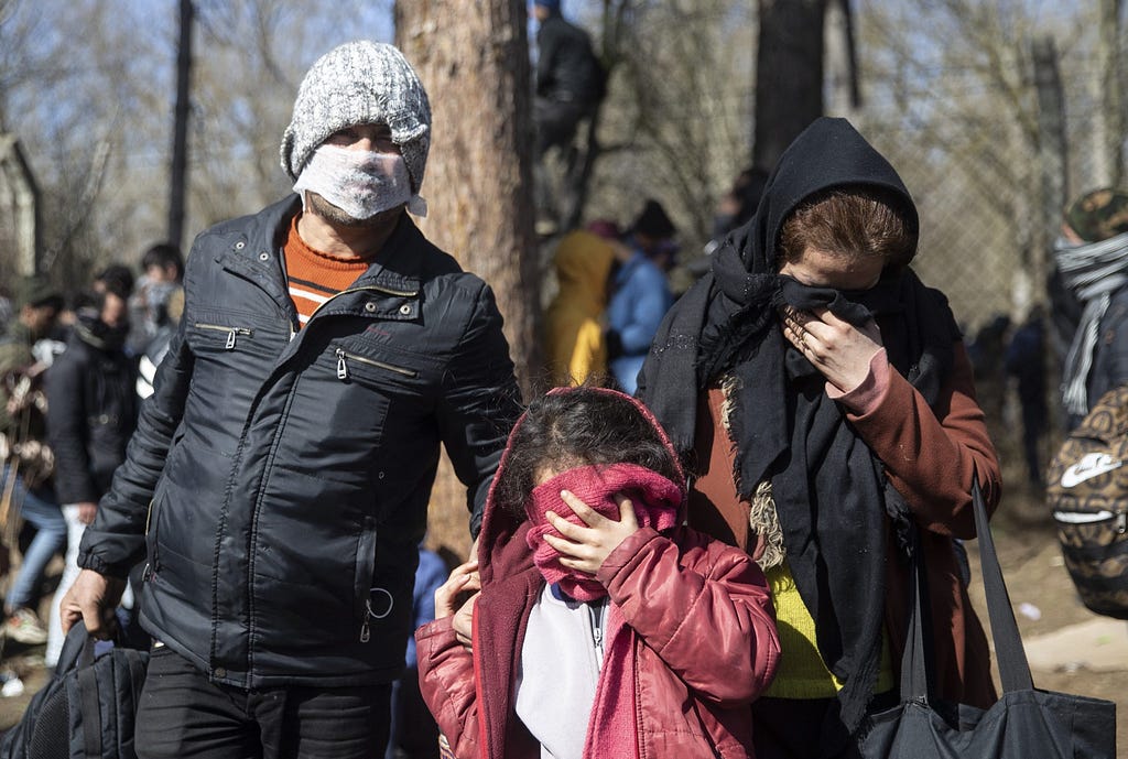 Unos migrantes cubren sus rostros para protegerse de los gases lacrimógenos lanzados por las fuerzas de seguridad griegas. (Getty Images)