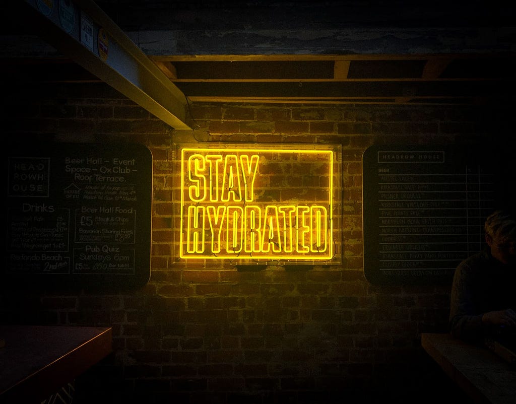 Yellow neon lights stating, “STAY HYDRATED”