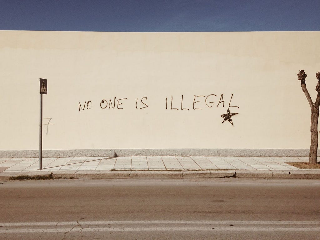 A wall with “No one is illegal” written on