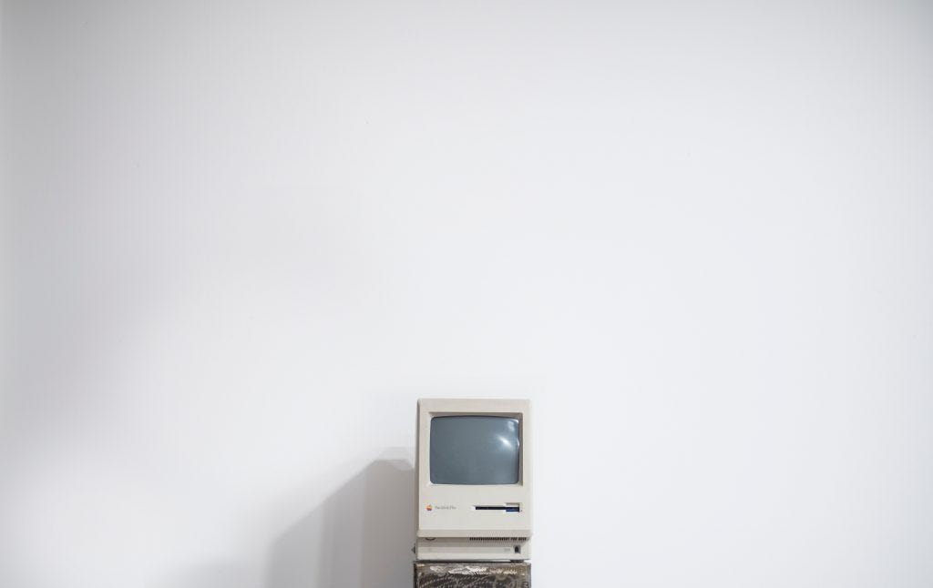 Old school mac computer against a big white wall