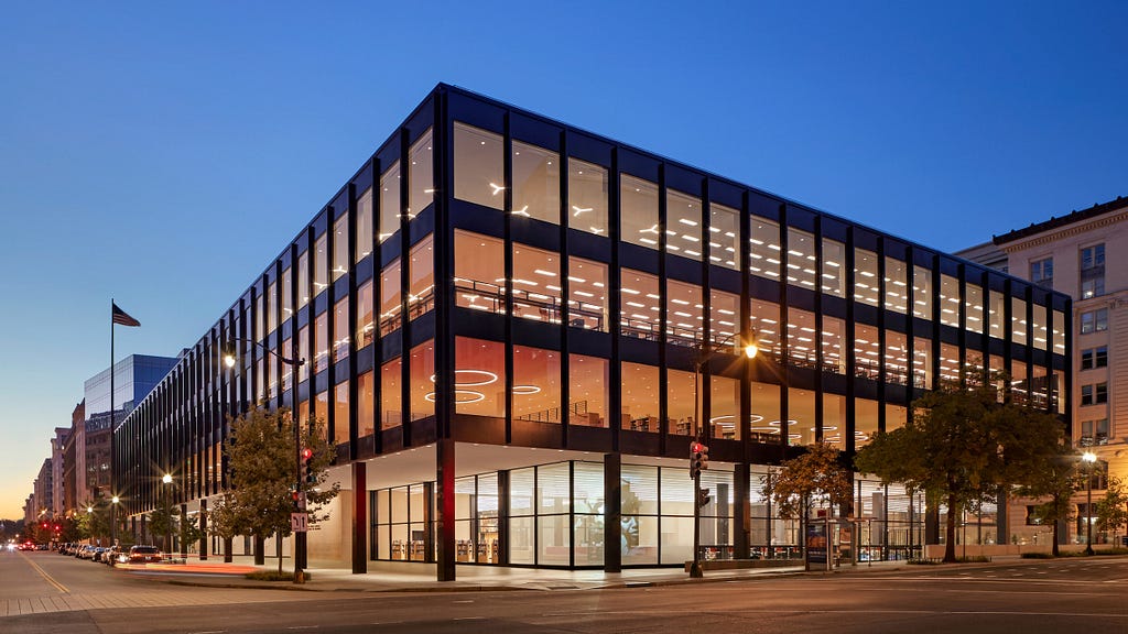 An exterior shot of a building at dusk. The building is four stories tall and extremely rectangular. It the DC downtown public library.