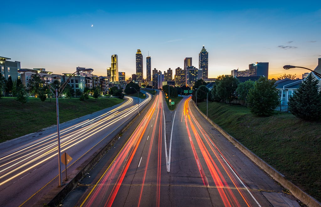 Picture of freeways going into a city, ultra-fast photo shows cars as streaks of multi colored lights.