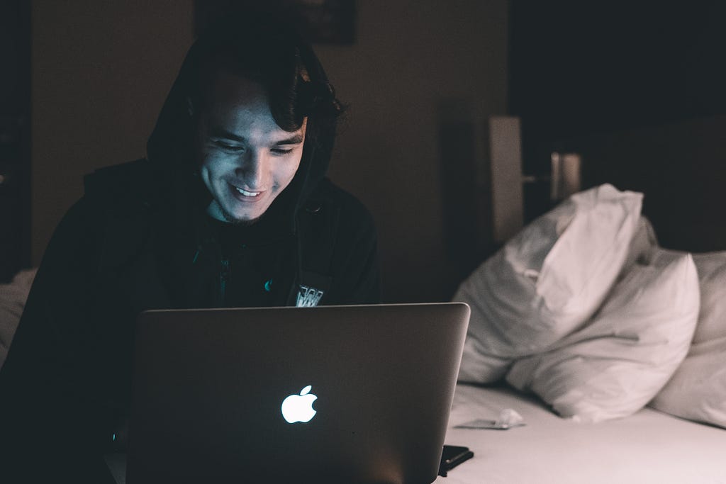 A man sitting on his bed using his computer, this is used to depict the significance technology has today.