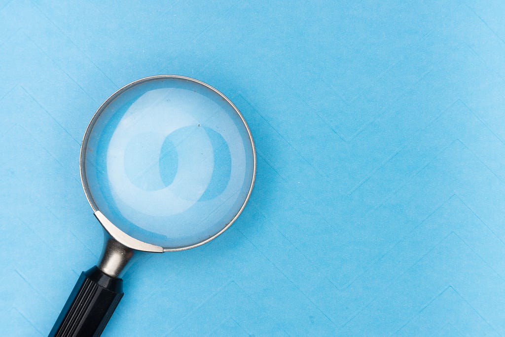 Close up of a magnifying glass on a bright blue background