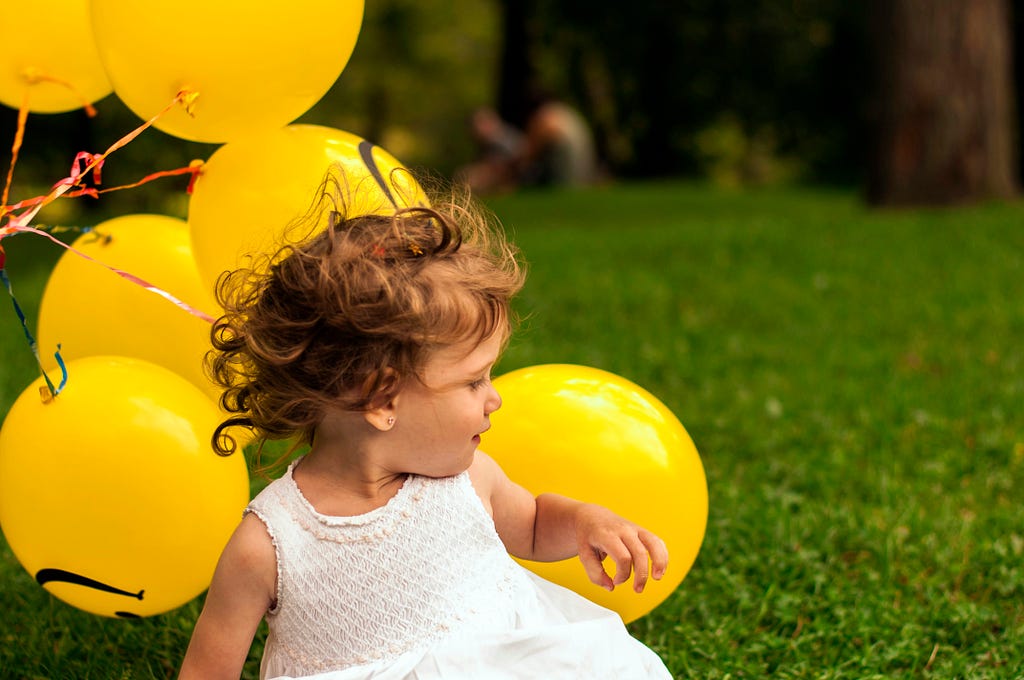 A beautiful toddler girl among yellow balloons