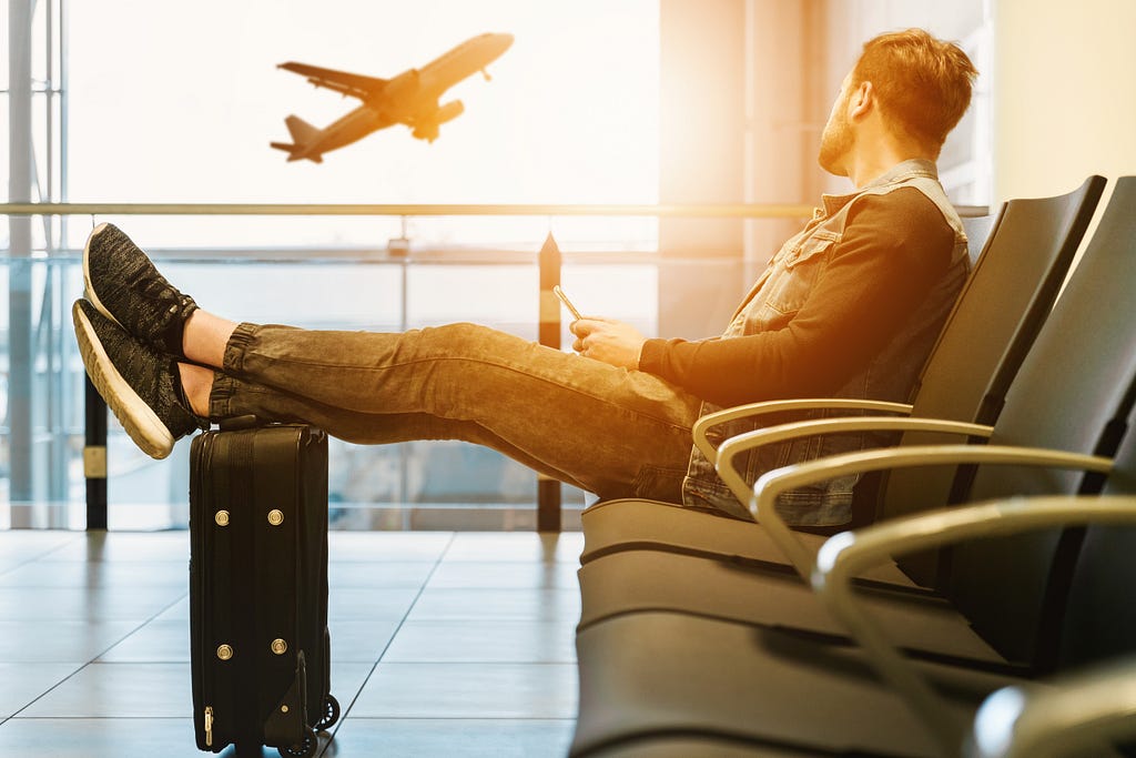 man at the airport looking at a plane setting off