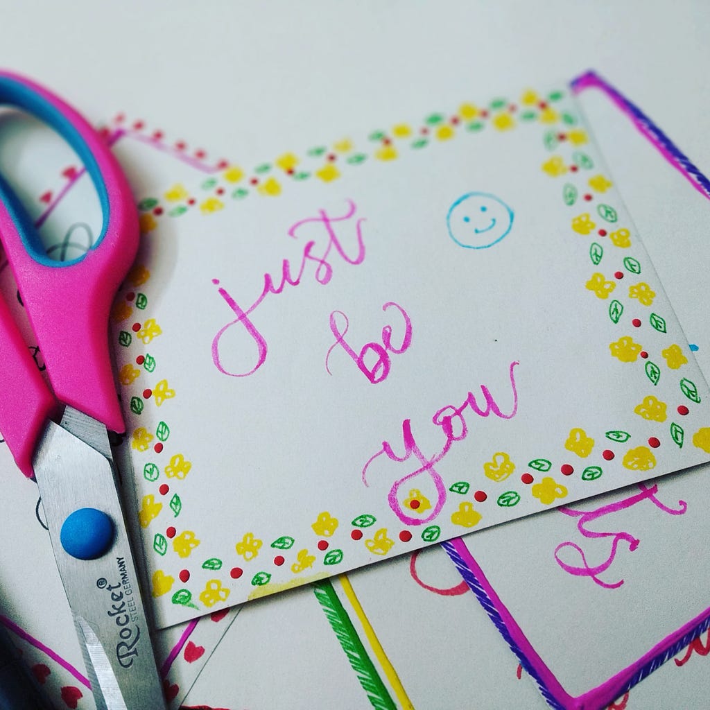 pretty pink calligraphy with the words “just be you” with a smiley face on a post card